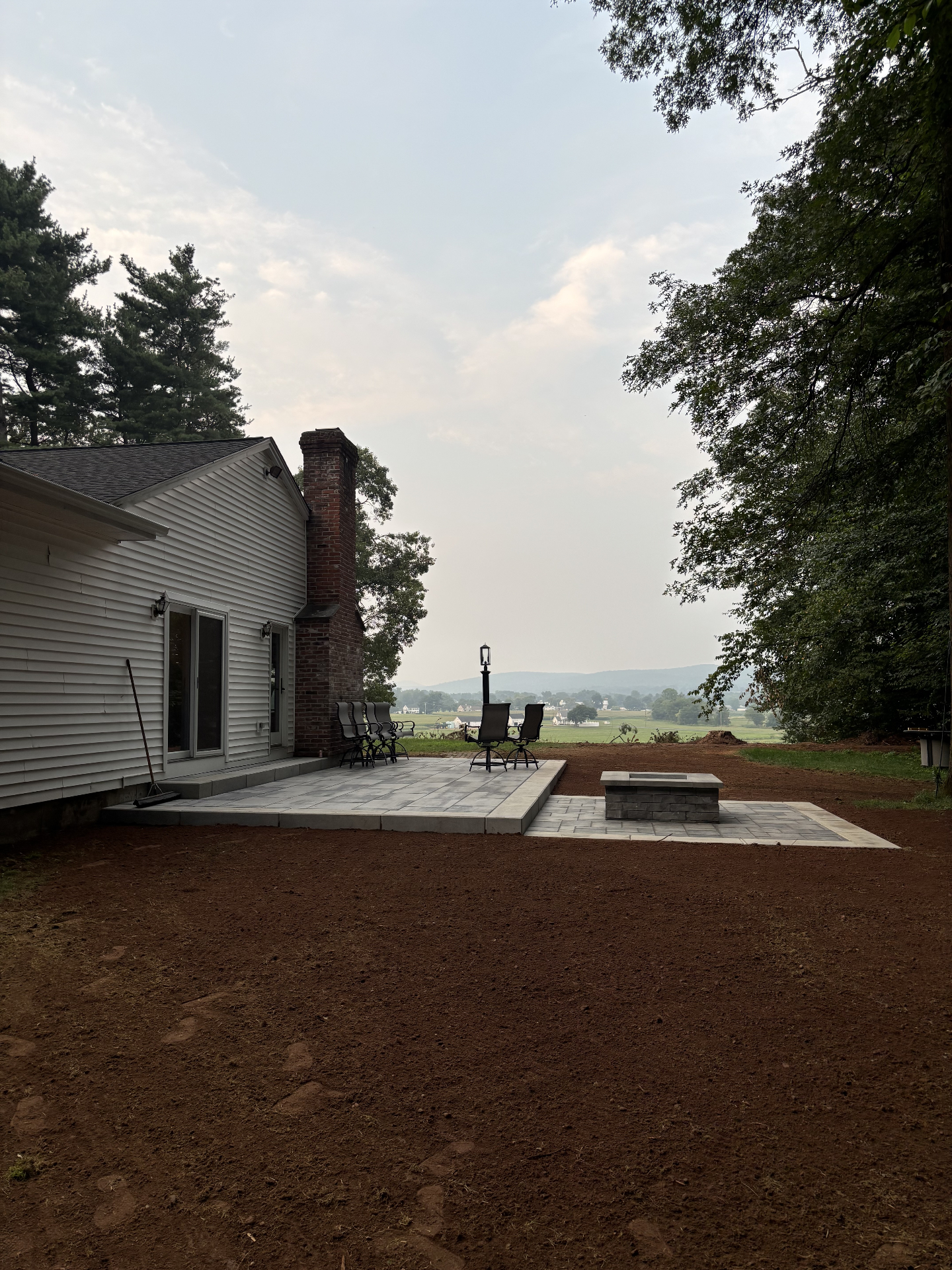 Finished paver patio with a stone fire pit overlooking the valley