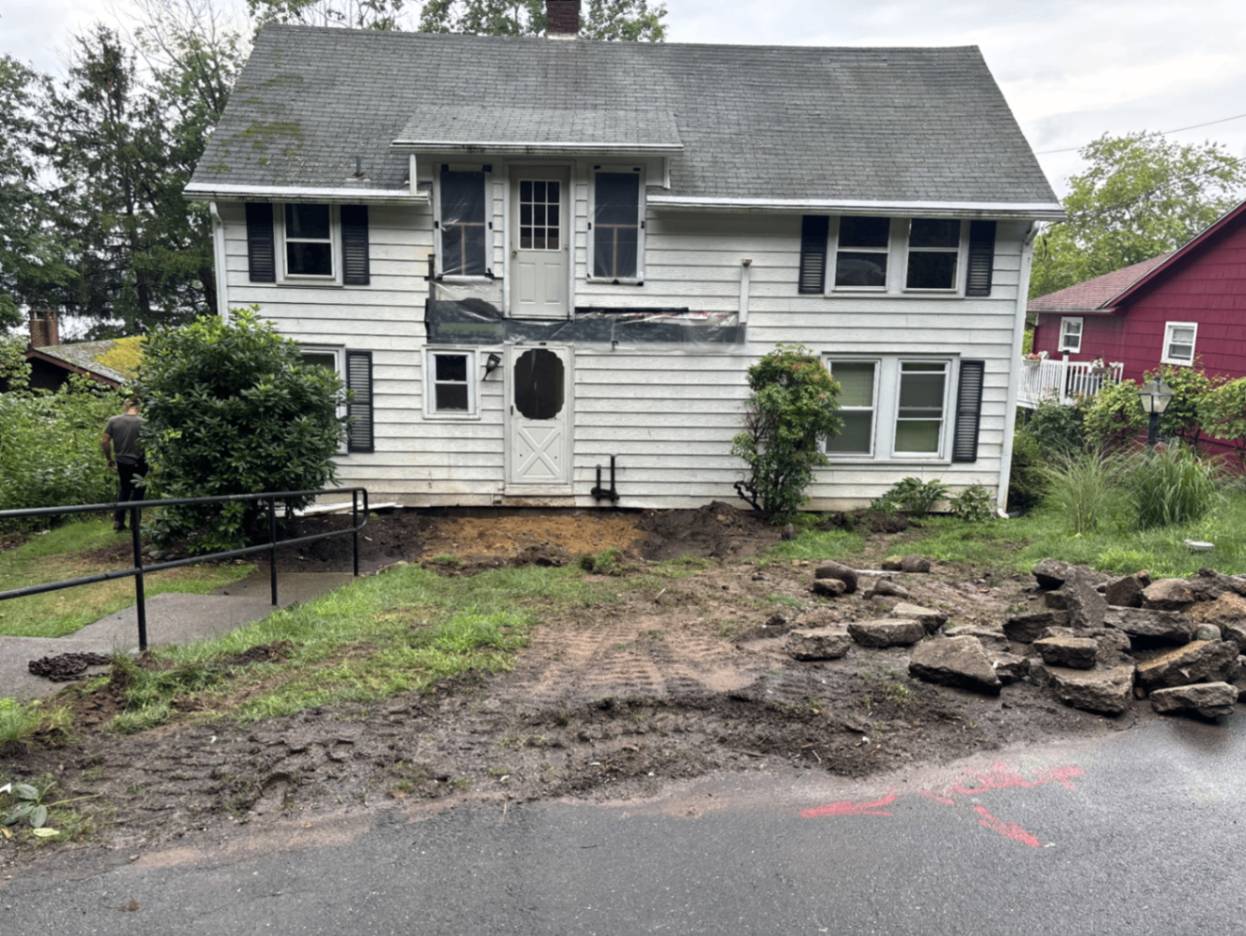Original white lake house with entry torn out and yard excavated