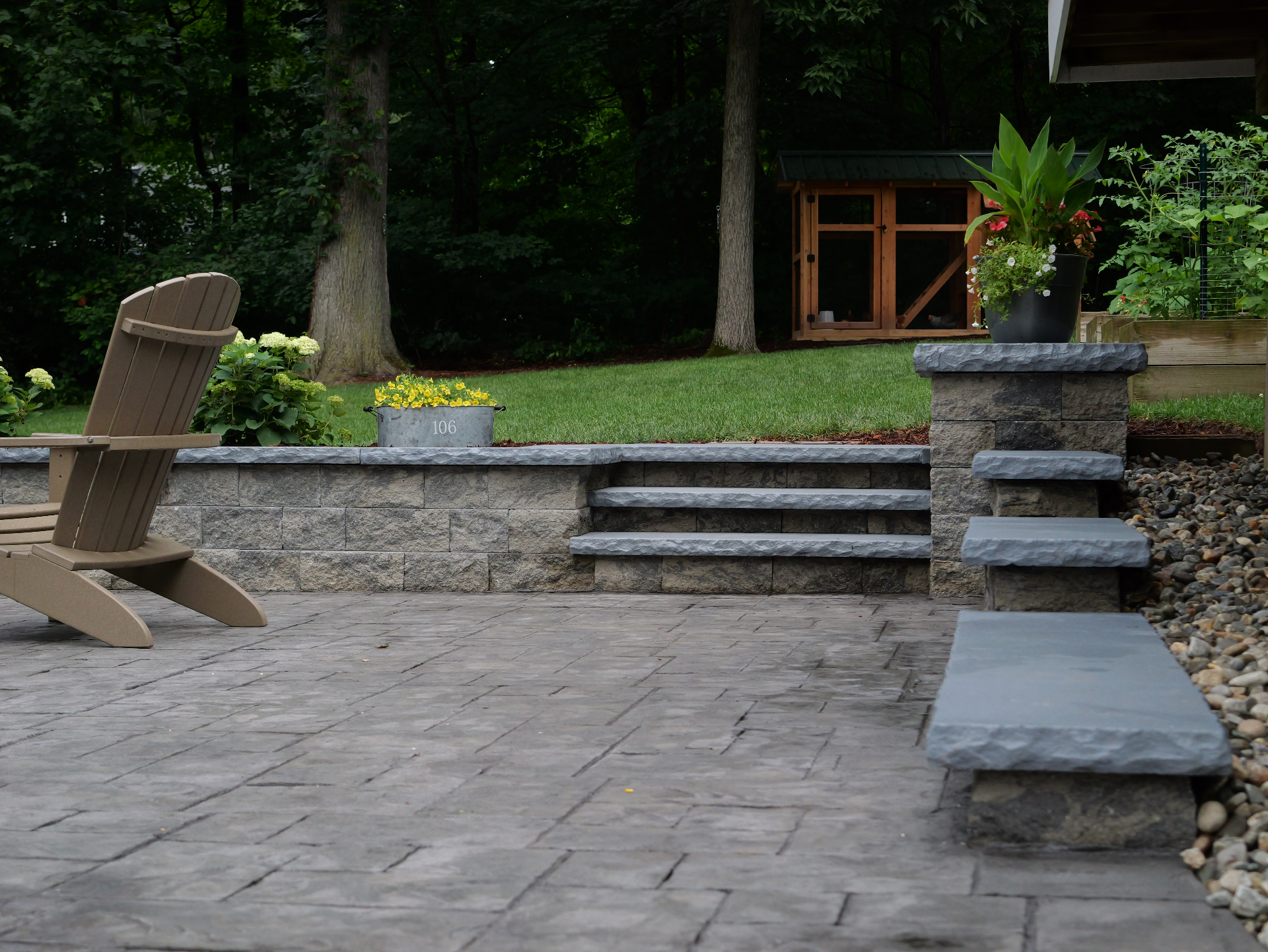 Finished block retaining wall with bluestone-capped steps and stamped concrete patio