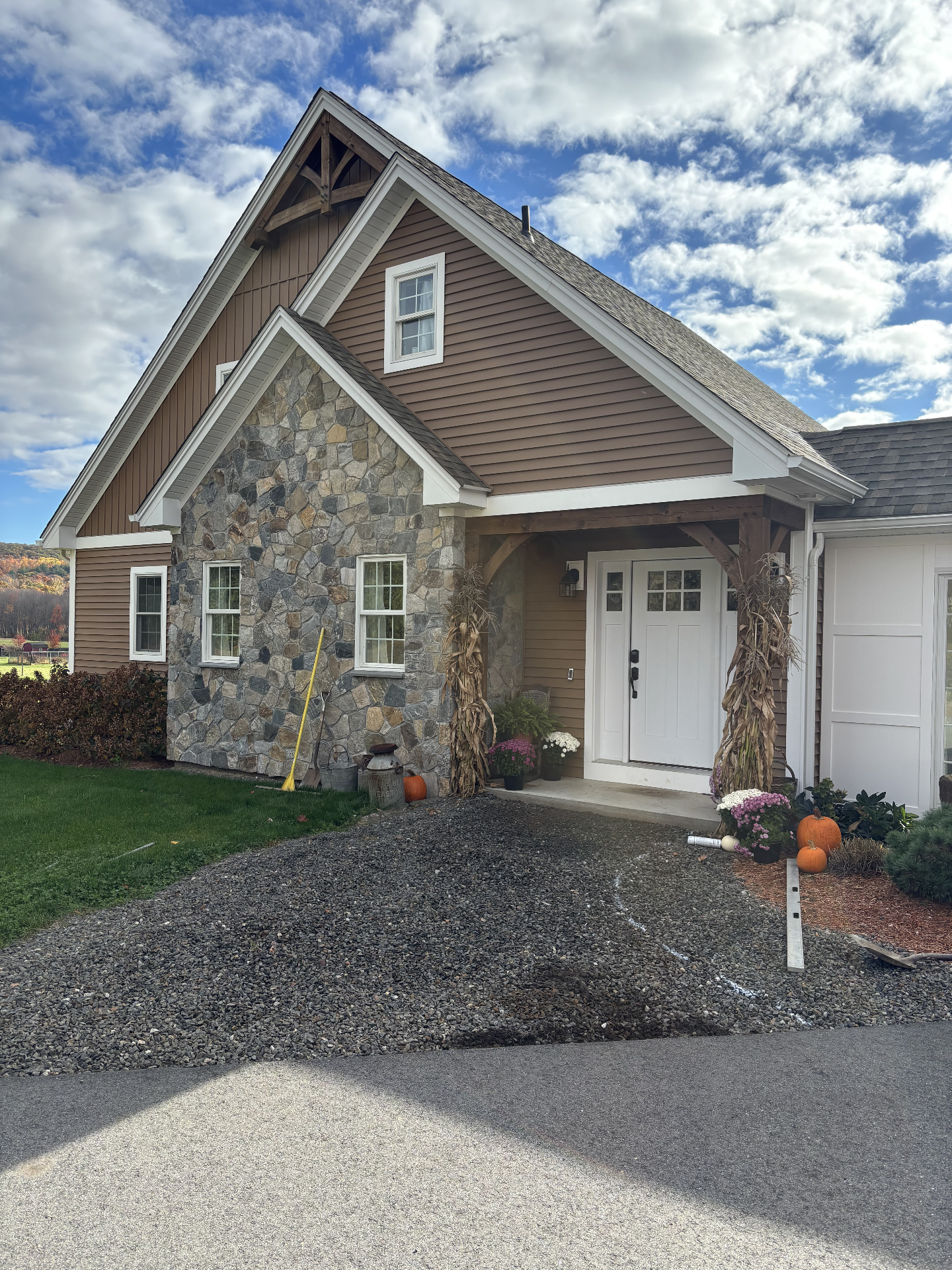 Gravel entry area in front of a stone and shingle home before the walkway was installed