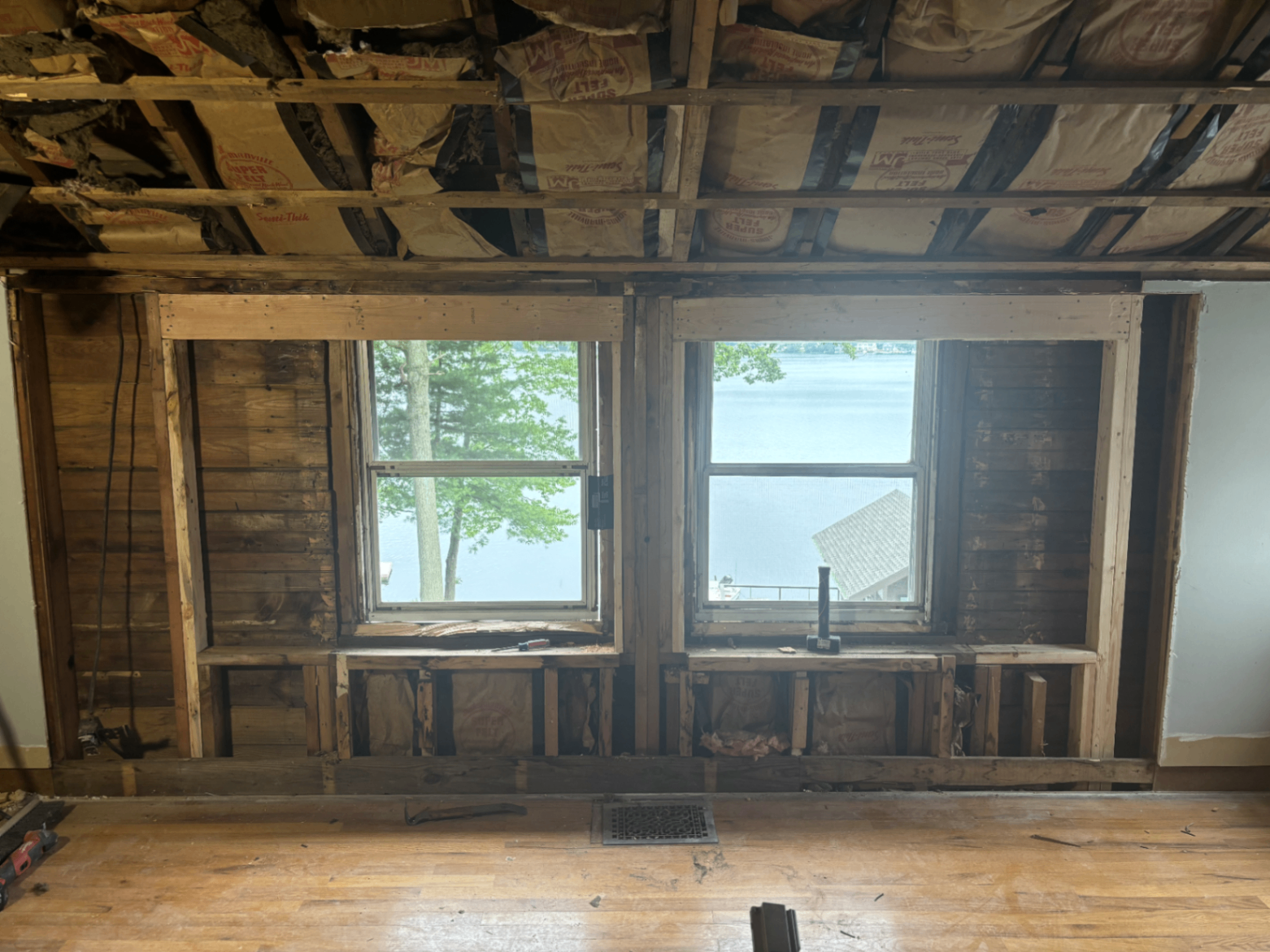 Interior wall stripped to framing with old windows facing the lake