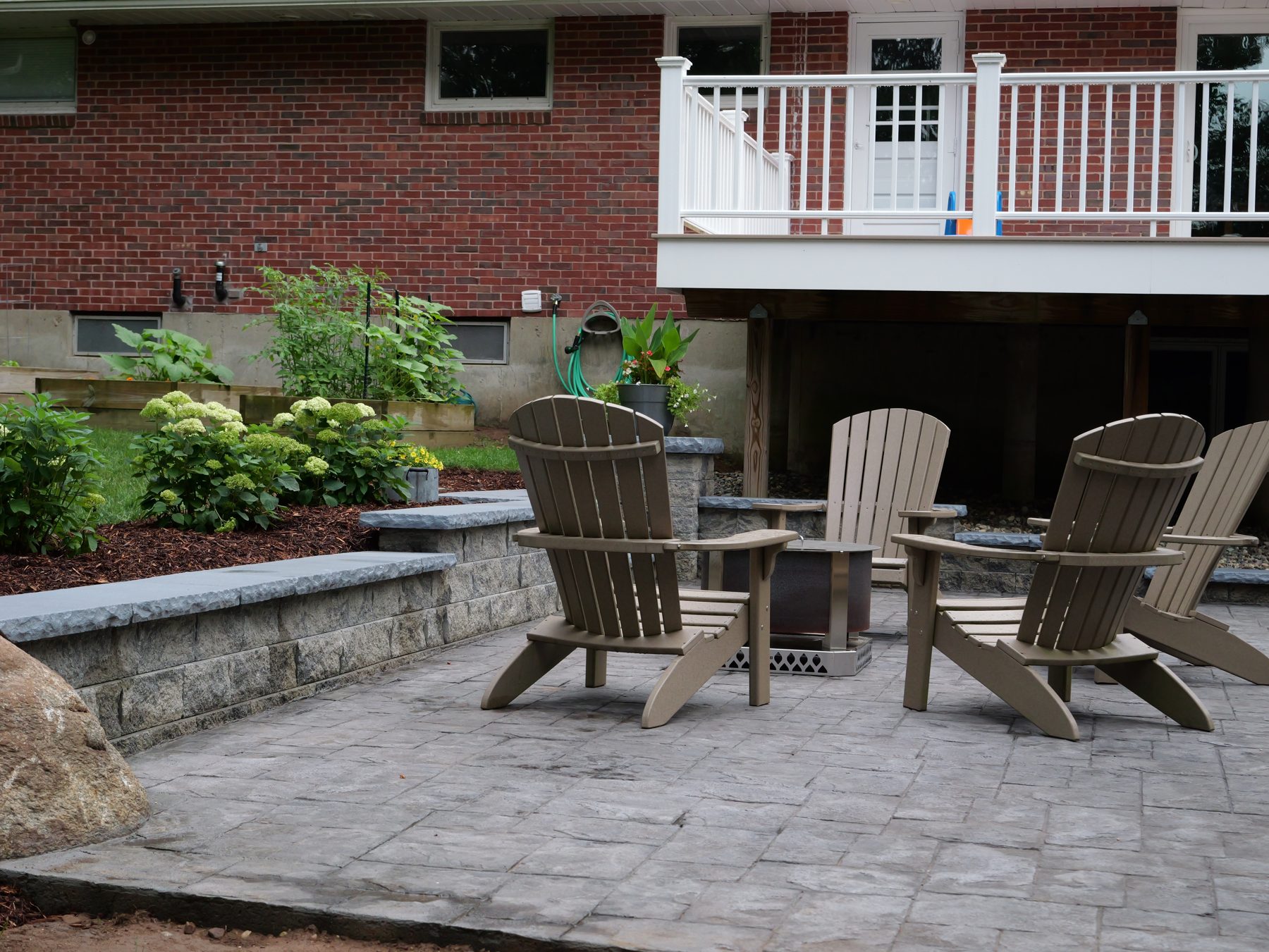 Stamped concrete patio seating area with stone wall